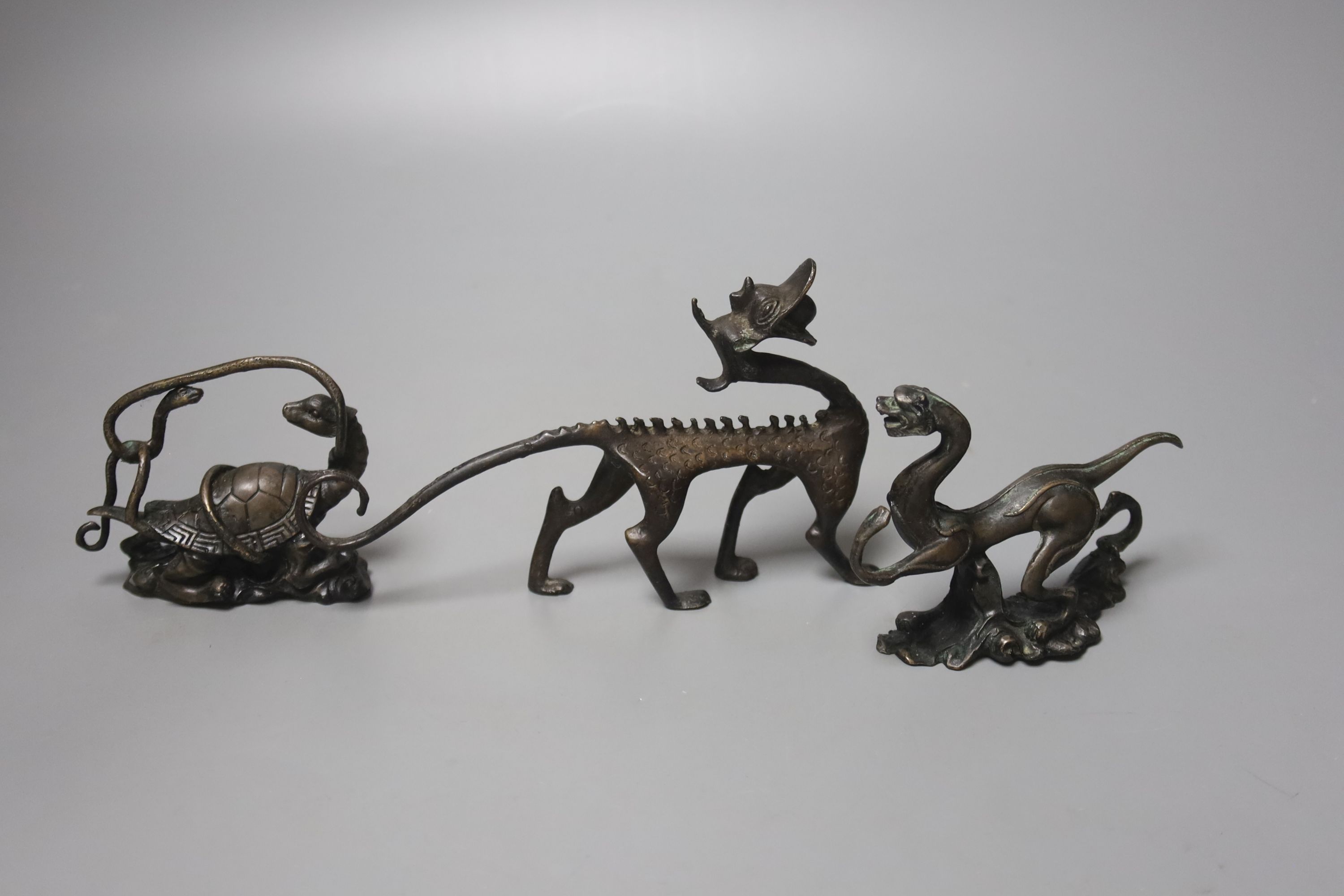 Three Chinese bronze figural brush rests, largest 15.5cm wide